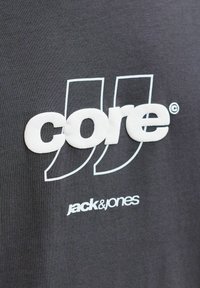 Szürke pamut póló dombornyomott fehér "core" és "jack & jones" logókkal. Simaságot sugárzó, egyszerű, modern design.