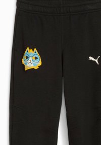 Sorte joggebukser lavet af blød stof, med et farverigt kattegraphic og et hvidt Puma-logo på siden. Elastisk talje.