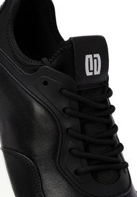Zwart sportief schoen met een glad leren bovenwerk, stoffen tong, zwarte veters en een logopatch met een opvallend ontwerp.