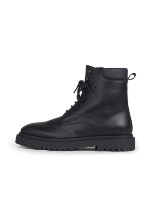 Schwarzer Lederknöchelboot mit Schnürung vorne, Zuglasche hinten und dicker Profilsohle für robusten Stil und Haltbarkeit.