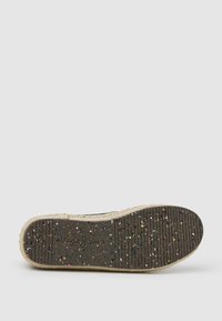 Suela de goma texturizada negra con motas multicolores, ribete de yute natural y logo grabado; las ranuras ofrecen agarre para tracción.