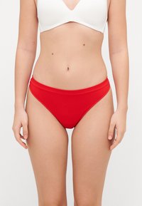 Red ribbed bikini bottoms with a high-rise waist, featuring a smooth texture and minimalistic design.