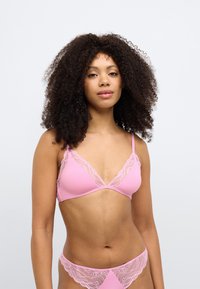 Růžová braletka s trojúhelníkovými košíčky, krajkovým lemem a nastavitelnými ramínky; spodní díl ve stejném stylu s krajkovými detaily. Hladká textura látky.