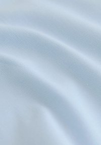 Svetlo modra tkanina z gladko teksturo in fino, enakomerno tkanino, ki prikazuje mehke, tekoče gube in subtilen sijaj.