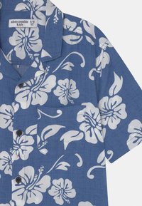 Blauwe korte mouwen button-up shirt met een witte hibiscus bloemenpatroon en borstzak, gemarkeerd met Abercrombie Kids maat 9/10.