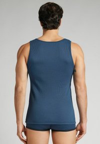 Mörkblå randig linne med en rundad halsringning, åtsittande design och lagerkant. Bärs med matchande mörkblå boxershorts, sett bakifrån.