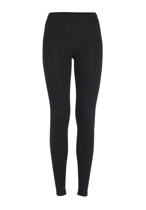 Gros plan d'une personne portant des leggings noirs taille haute et un haut blanc, montrant le bas du dos et les hanches.