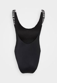 Maillot de bain sculptant noir avec un décolleté large et des bretelles larges, arborant un logo "Calvin Klein" blanc dans le dos. Tissu lisse, sans motifs.