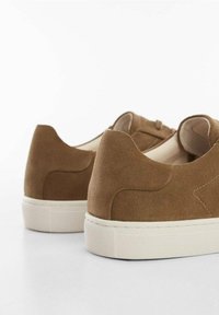 Baskets en daim marron à design à tige basse, dotées d'une finition texturée et d'une semelle en caoutchouc de couleur claire. Rehaussées de détails de coutures discrètes.
