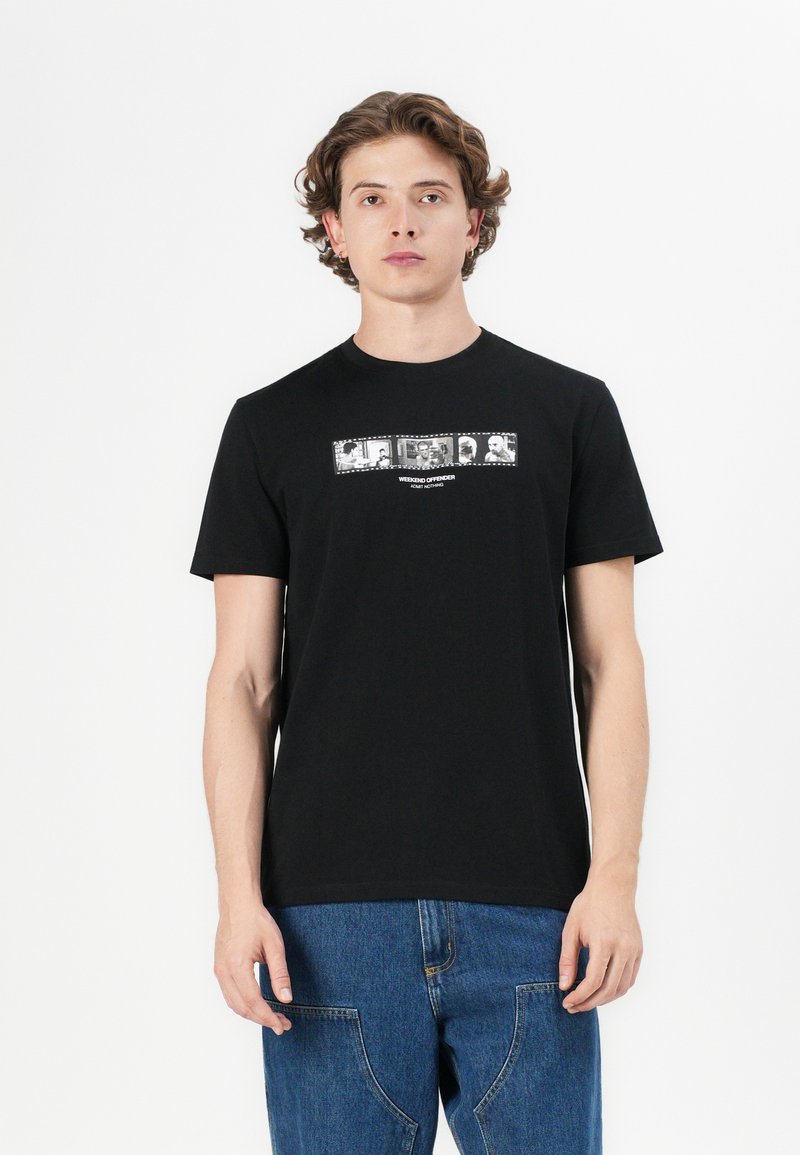 Sort bomulds t-shirt med korte ærmer og rund halsudskæring, med et rektangulært grafisk tryk i hvid og grå henover brystet.