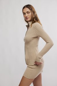 Μπεζ φόρεμα από πλεκτό ύφασμα με καλώδιο, κλείσιμο με φερμουάρ, υφή με ραβδώσεις, μακριά μανίκια και εφαρμοστή σιλουέτα.