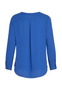 Blouse bleue à manches longues avec pli au dos, poignets boutonnés et ourlet arrondi, vue de dos sur fond blanc.