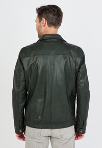 Donkergroene leren jas met een gladde textuur, een getailleerde pasvorm en knoopmanchetten; voorzien van een klassieke kraag en subtiele stikseldetails.