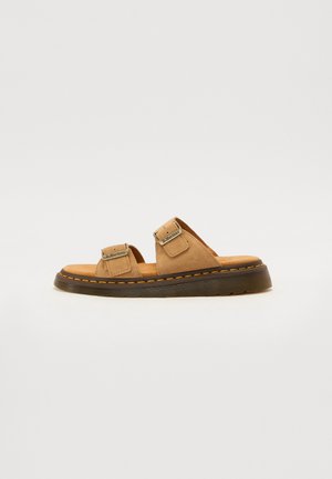 Bruine suède slipper sandalen met twee verstelbare riemen, een gewatteerde voetbed en een gestructureerde rubberen zool met oranje stiksels.