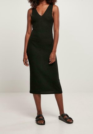 Robe midi noire côtelée avec un décolleté en V profond, une coupe ajustée et une texture lisse. Associée à des sandales à glissière noires. Style simple et décontracté.