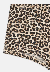 Løveprikkede shorts med en blød, ribbet tekstur. Har mørkebrune pletter på en beige baggrund, afsluttet med kontrasterende syninger langs kanten.