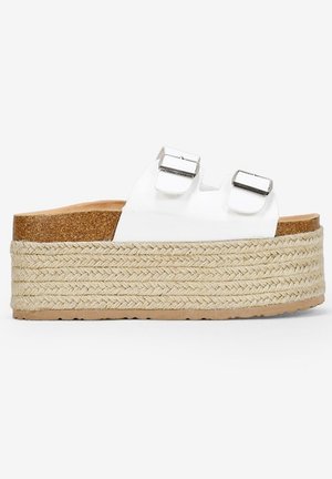 Sandalias de plataforma blancas con dos hebillas plateadas ajustables, media suela de yute trenzado y plantilla de corcho, que presenta una suela de goma plana texturizada.