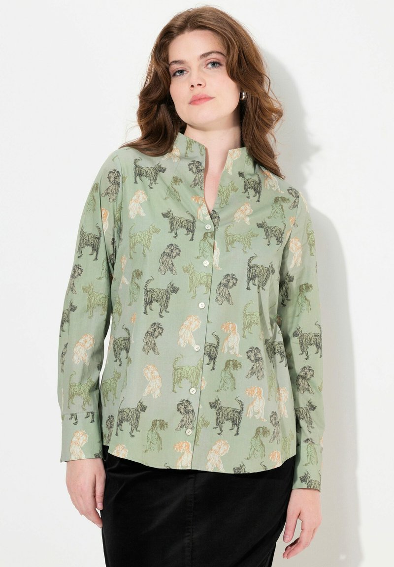 Camisa de manga larga con botones en tela verde claro, que presenta un diseño de estampado animal con varios perros contorneados en negro y acentos en naranja.