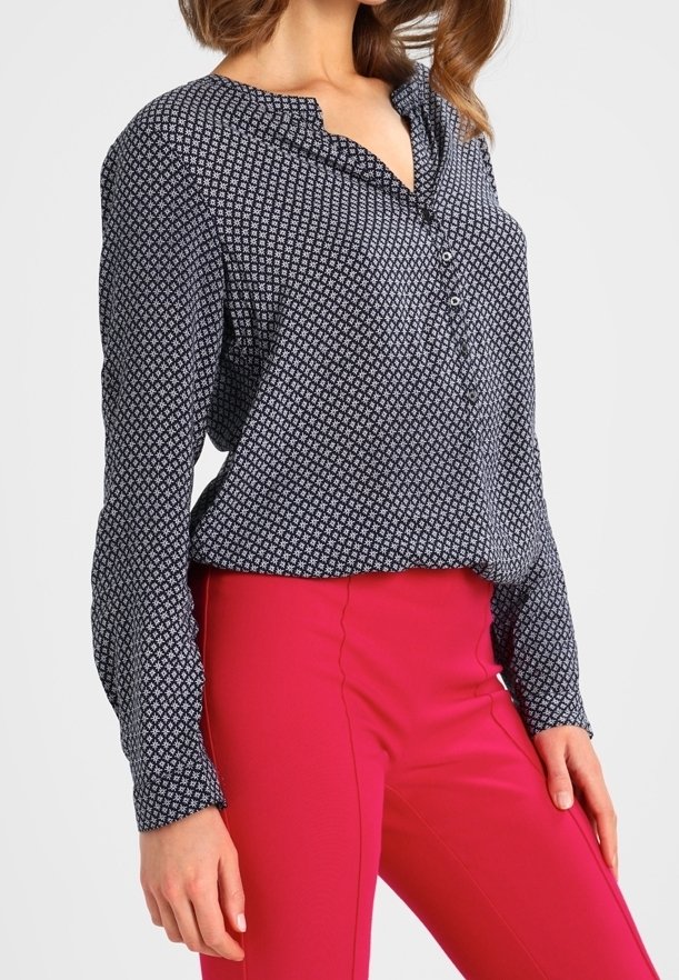 Blusa a maniche lunghe di colore blu navy con motivo, con un'unica chiusura a bottone sul davanti e una vestibilità comoda, abbinata a pantaloni aderenti di un brillante colore rosa.}}