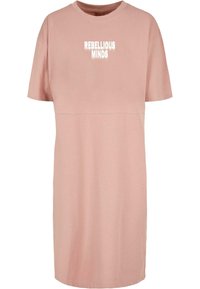 Robe en coton rose avec des manches courtes, un col rond et le texte "REBELLIOUS MINDS" imprimé à l'avant en blanc. Design simple et ample.