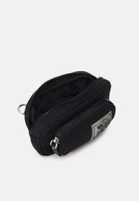 Černá nylonová taštička s dvojitými zipovými přihrádkami, hladkým povrchem a stříbrnou nášivkou loga na přední straně. Kompaktní a praktický design.