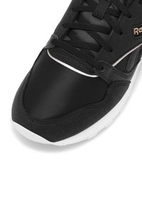 Černá sportovní bota s hladkým syntetickým a texturovaným vrškem, která má bílé akcenty na podešvi a kontrastní švy.