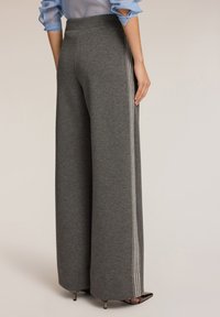Grijze wijde broek met een zachte textuur, voorzien van witte zijstrepen. Ontworpen met een hoge taille voor een ontspannen pasvorm.