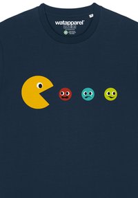 Das marineblaue T-Shirt hat ein gelbes Pac-Man-Graphic mit vier farbigen, runden Gesichtern: rot, türkis und limonengrün, die verschiedene Gesichtsausdrücke zeigen.