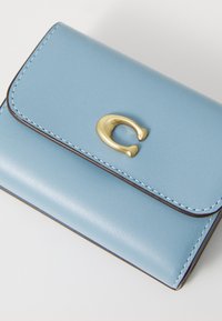 Sky blue leather wallet with a gold-tone C-shaped clasp, dark edge stitching, and a smooth texture. Compact rectangular design.