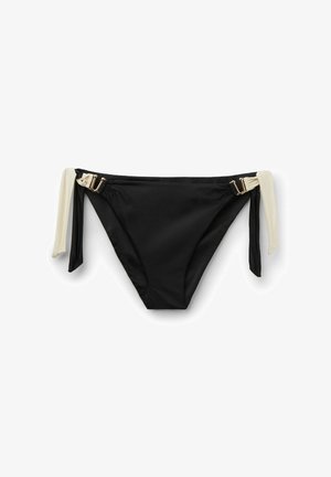 Bas de bikini noir avec côtés beiges noués et détails de boucles dorées sur fond blanc.