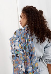 Écharpe légère bleue avec un motif imprimé ludique de personnages de bande dessinée. Le tissu est translucide avec une texture lisse.