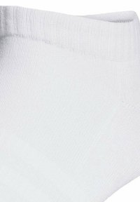 Chaussette de cheville en coton blanc avec un revers côtelé, un orteil sans couture et une texture douce, conçue pour le confort et la respirabilité.