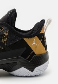 Czarne buty do koszykówki z złotymi akcentami, siateczkową cholewką, teksturowanym zapiętkiem, gumową podeszwą oraz charakterystycznym logo Jumpman z boku.