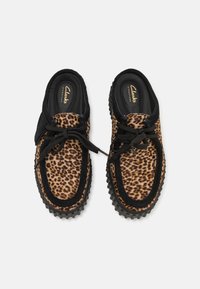 Leopard-print suede shoes with black accents and rubber soles. Features round toe, lace-up design, and textured upper.