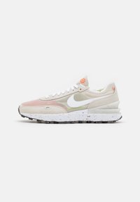 Tenisky Nike s béžovým a růžovým svrškem, síťovinou, bílým logem, texturovanou mezipodrážkou a černou podrážkou s barevnými skvrnami.