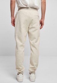 Lichtbeige sweatpants met een relaxte pasvorm, voorzien van een achterzak, elastische tailleband en geribde boorden. Gecombineerd met witte sneakers.