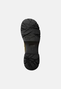 Black rubber shoe sole with textured tread for traction, featuring angular patterns and a central logo. Solid construction, durable material.