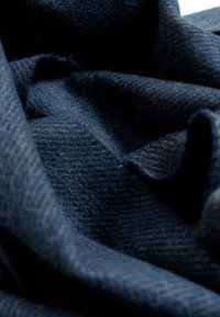 Tela de lana azul marino con una superficie suave y texturizada. El material presenta patrones sutiles y variaciones en el grosor, creando profundidad.