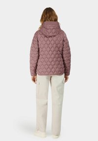 Vadderad, huvad lila pufferjacka med diamantmönster, i kombination med beige cargobyxor med sidofickor och avslappnad passform.