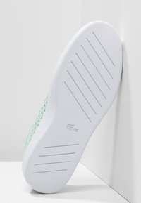 Světle zelené texturované síťované tenisky s bílou gumovou podrážkou, která má horizontální drážky a malé logo.