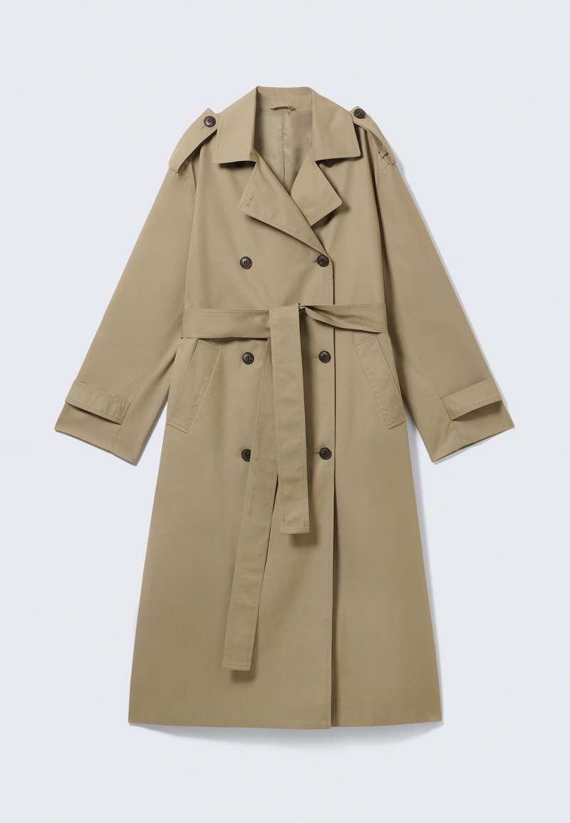 Trench-coat beige croisé avec larges revers, pattes d'épaule boutonnées, ceinture à la taille, poches latérales et poignets boutonnés.