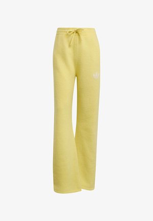 Pantalon de survêtement large en polaire jaune avec taille élastique et cordon, avec un petit logo Adidas blanc sur la cuisse gauche.