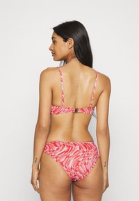 Conjunto de bikini rosa com um padrão de design com formas e texturas variadas. Alças finas ajustáveis com um fecho nas costas.