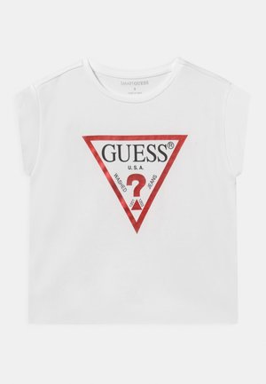 Weißes ärmelloses Shirt mit rotem Dreieckslogo, das "GUESS U.S.A." und ein großes rotes Fragezeichen in der Mitte zeigt.