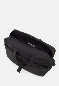 Black nylon bag with two top handles, zip closure, and multiple internal pockets. Smooth texture and rectangular shape.