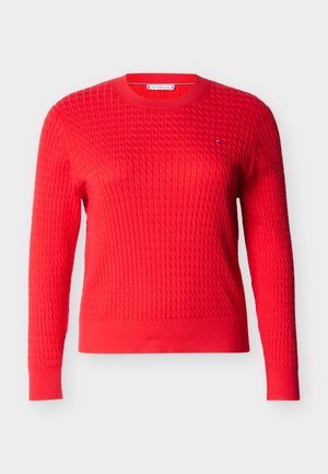 Pull en tricot rouge avec un motif texturé, col rond et manches longues. Présentant un petit logo de marque sur la poitrine.