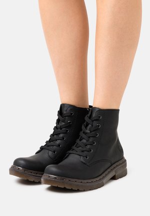 Bottines en cuir noir avec bout rond, lacets à l'avant et semelle en caoutchouc texturé avec des détails de couture. Finition lisse sur l'ensemble.