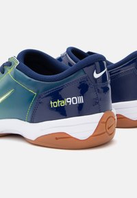 Par žutih i zelenih Nike Total 90 III tenisica sa bijelim srednjim potplatima i gumiranim vanjskim potplatima, prikazane stražnje i bočne detalje.