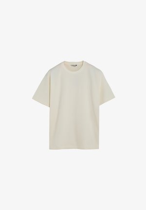 Camiseta de manga corta color crema hecha de algodón suave. Diseño de cuello redondo con un ajuste relajado y bajo recto. Sin patrones o acentos visibles.