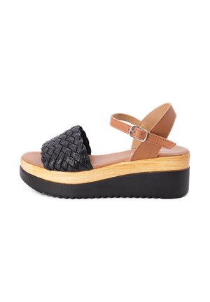Sandali platform in pelle intrecciata nera con cinturino alla caviglia beige, caratterizzati da un sottopiede effetto legno e una suola in gomma nera con scanalature.